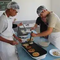 des jeunes preparent des crepes sur des plaques chauffantes